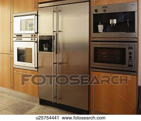 Stock Image - Stainless steel American style fridge-freezer and wall-mounted double oven. Fotosearch