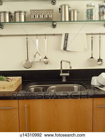 Stainless steel canisters on shelves above underset sink in granite worktop View Large Photo Image Stock Image - Stainless steel canisters on shelves above underset sink in granite worktop. Fotosearch