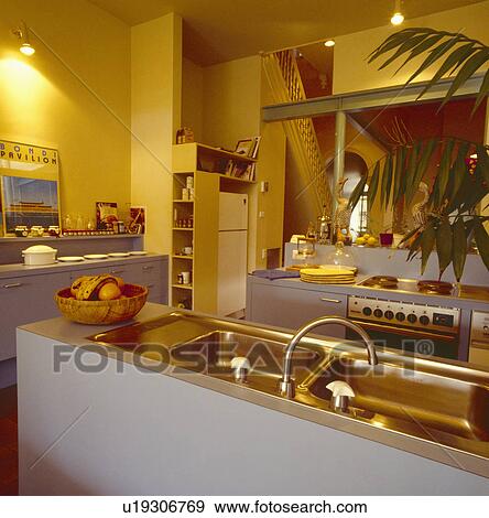 Stainless steel double sink and mixer tap in island unit in modern yellow kitchen with lighted spotlights View Large Photo Image Stock Photo - Stainless steel double sink and mixer tap in island unit in modern yellow kitchen with lighted spotlights. Fotosearch