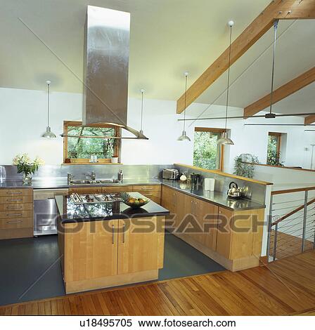 Stock Photography - Stainless steel extractor above island unit in modern barn conversion kitchen . Fotosearch