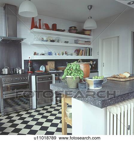 Stainless steel oven and dishwasher below shelving in modern kitchen with black & white chequerboard flooring View Large Photo Image Stock Photo - Stainless steel oven and dishwasher below shelving in modern kitchen with black & white chequerboard flooring. Fotosearch