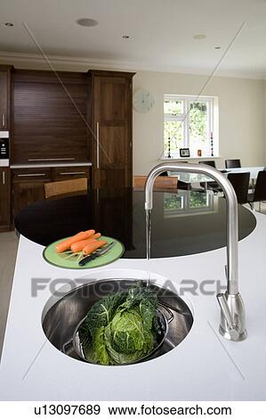 Stainless steel tap pouring water into undermounted stainless steel Francke sink in white granite worktop View Large Photo Image Stock Photo - Stainless steel tap pouring water into undermounted stainless steel Francke sink in white granite worktop. Fotosearch