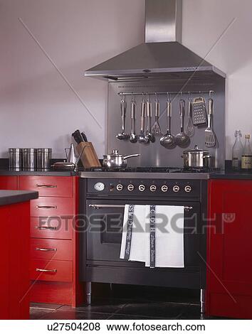 Steel extractor above black oven in fitted red units View Large Photo Image Stock Photo - Steel extractor above black oven in fitted red units. Fotosearch
