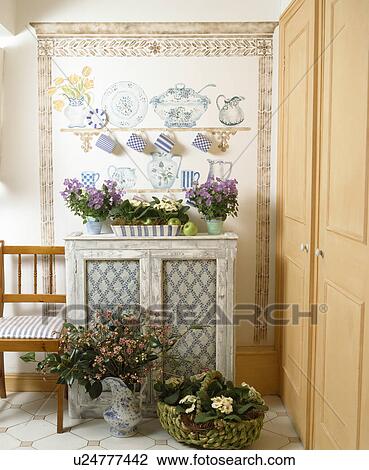 Stencilled faux dressser above painted cupboard in country hall with jugs and baskets of fresh flowers View Large Photo Image Stock Image - Stencilled faux dressser above painted cupboard in country hall with jugs and baskets of fresh flowers. Fotosearch