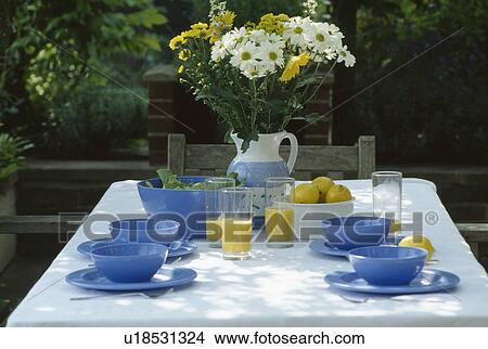 Still-Life of blue cups and plates on table with white cloth and vase of white and yellow daisies View Large Photo Image Picture - Still-Life of blue cups and plates on table with white cloth and vase of white and yellow daisies. Fotosearch