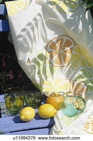 Stock Photo - Still-Life of fabric stencilled with orange segments on blue wooden bench with lemons and limes in enamel dish. Fotosearch