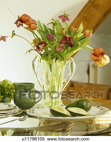 Still-Life of orange tulips in glass vase on table with green pottery jug View Large Photo Image Stock Photography - Still-Life of orange tulips in glass vase on table with green pottery jug. Fotosearch
