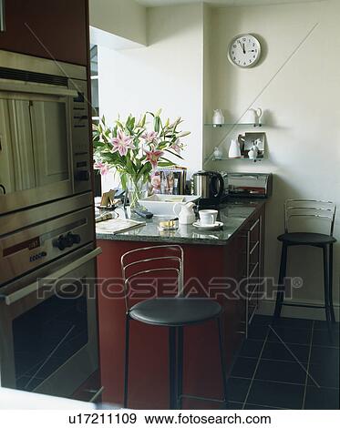 Stools at breakfast bar on red fitted unit with granite worktop View Large Photo Image Stock Photo - Stools at breakfast bar on red fitted unit with granite worktop. Fotosearch