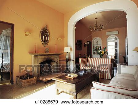 Stock Photo - Striped sofa and wooden table in living room in small Mallorcan house. Fotosearch