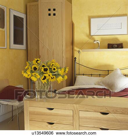 Sunflowers on chest below bed in yellow bedroom View Large Photo Image Stock Photograph - Sunflowers on chest below bed in yellow bedroom. Fotosearch