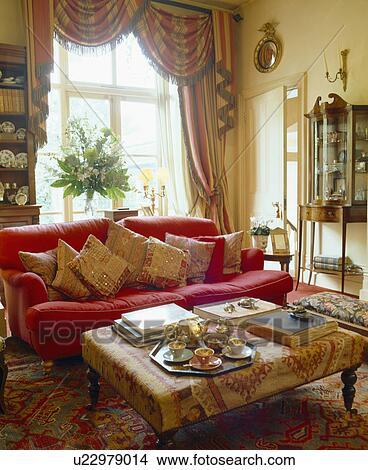 Swagged and tailed curtains in traditional living room with pink sofa piled with mirrored cushions View Large Photo Image Picture - Swagged and tailed curtains in traditional living room with pink sofa piled with mirrored cushions. Fotosearch