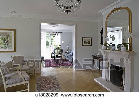 Swedish oak-strip parquet flooring in country hall with gilt mirror above fireplace and open double doors to living room View Large Photo Image Stock Photo - Swedish oak-strip parquet flooring in country hall with gilt mirror above fireplace and open double doors to living room. Fotosearch