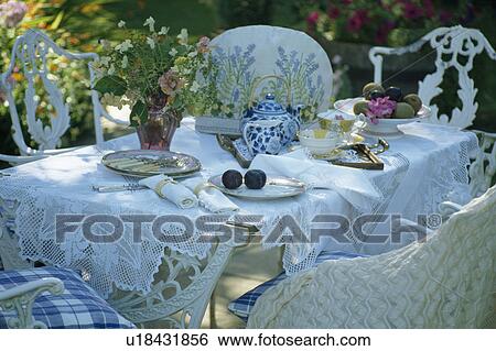 Table set for tea with vase of fresh flowers and white lace-edged cloth in summer garden View Large Photo Image Stock Photograph - Table set for tea with vase of fresh flowers and white lace-edged cloth in summer garden. Fotosearch