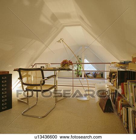 Tall floor lamp above desk with chrome and cane chair in modern attic study with briefcase on cream carpet View Large Photo Image Stock Image - Tall floor lamp above desk with chrome and cane chair in modern attic study with briefcase on cream carpet. Fotosearch