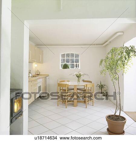 Tall houseplant and white ceramic tiled floor in white country kitchen with wooden chairs and formica-topped table View Large Photo Image Picture - Tall houseplant and white ceramic tiled floor in white country kitchen with wooden chairs and formica-topped table. Fotosearch