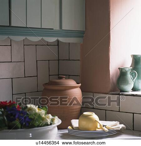 Picture - Terracotta pot on worktop below white tiles in traditional kitchen. Fotosearch