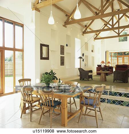 Tiled-topped dining table in open-plan barn conversion with split-level floor View Large Photo Image Stock Photo - Tiled-topped dining table in open-plan barn conversion with split-level floor. Fotosearch