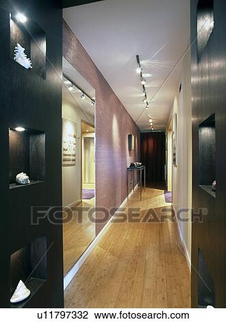 Stock Image - Track lighting and wooden flooring in narrow hall corridor in modern apartment. Fotosearch