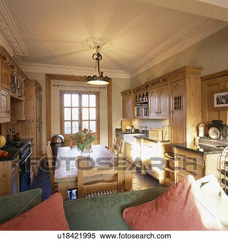 Stock Photography - Traditional dining room and kitchen with wooden table and chairs and fitted units. Fotosearch