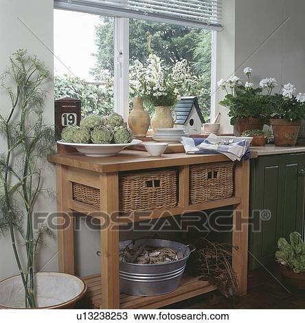 Stock Image - Traditional kitchen with wicker storage baskets in small pine table. Fotosearch