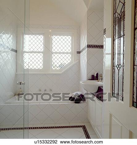 Stock Image - Traditional white tiled bathroom with black edging tiles. Fotosearch