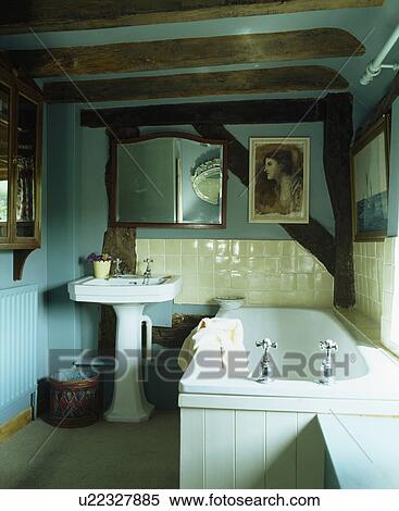 Stock Photography - Turquoise cottage bathroom with beamed ceiling and white bath and basin. Fotosearch