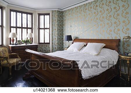 Turquoise+gold Osborne+Little wallpaper in traditional bedroom with oak antique lit bateau bed View Large Photo Image Stock Photo - Turquoise+gold Osborne+Little wallpaper in traditional bedroom with oak antique lit bateau bed. Fotosearch