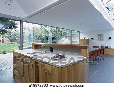 Stock Image - Undermounted sink in solid oak island unit in modern openplan kitchen and dining room extension. Fotosearch
