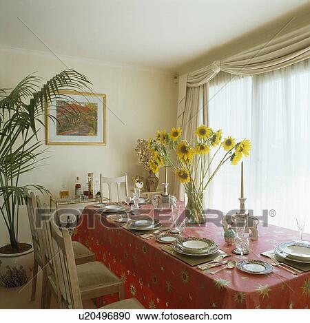 Vase of yellow sunflowers on table with red cloth in cream dining room View Large Photo Image Stock Image - Vase of yellow sunflowers on table with red cloth in cream dining room. Fotosearch