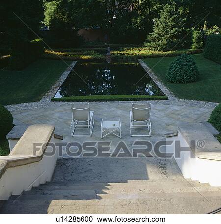 View down stone steps to chairs on paved terrace in front of rectangular pond in formal garden View Large Photo Image Stock Image - View down stone steps to chairs on paved terrace in front of rectangular pond in formal garden. Fotosearch