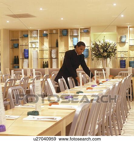 Waiter setting tables at modern London restaurant designed by Terence Conran View Large Photo Image Stock Photo - Waiter setting tables at modern London restaurant designed by Terence Conran. Fotosearch