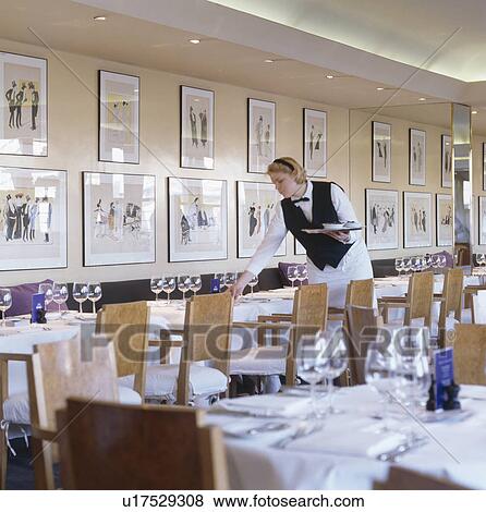 Waitress setting tables at modern London restaurant designed by Terence Conran View Large Photo Image Stock Photo - Waitress setting tables at modern London restaurant designed by Terence Conran. Fotosearch