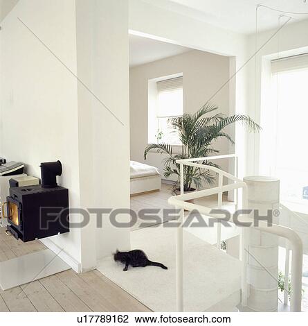 Wall-mounted black stove on wall of modern white open-plan landing with view of bedroom View Large Photo Image Stock Image - Wall-mounted black stove on wall of modern white open-plan landing with view of bedroom . Fotosearch