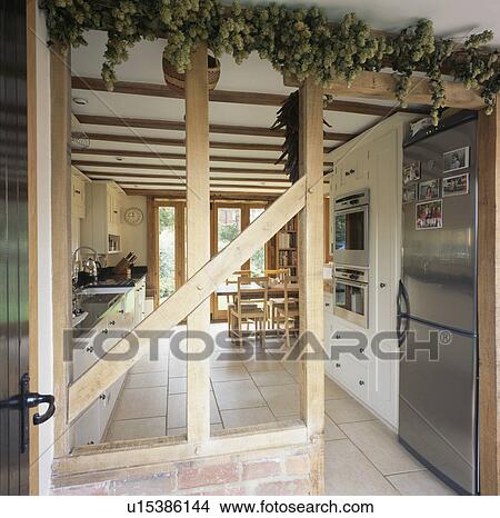 Picture - Wall with plaster removed to expose beams with hop bine in country kitchen. Fotosearch