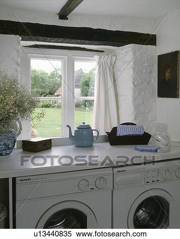 Stock Photography - Washing machine and tumble-dryer below window in cottage utility room. Fotosearch