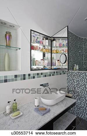 White bowl-style basin on Carrera marble-topped vanity unit below recessed wall cabinet with mirrored door View Large Photo Image Picture - White bowl-style basin on Carrera marble-topped vanity unit below recessed wall cabinet with mirrored door. Fotosearch