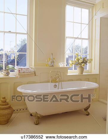 White clawfoot bath below windows in traditional white bathroom View Large Photo Image Stock Image - White clawfoot bath below windows in traditional white bathroom. Fotosearch