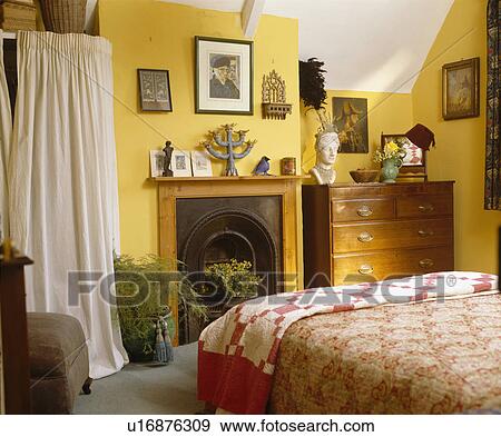 White curtain on alcove storage beside pine fireplace in yellow cottage bedroom View Large Photo Image Stock Photo - White curtain on alcove storage beside pine fireplace in yellow cottage bedroom. Fotosearch