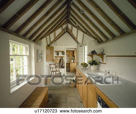 White double sink in galley kitchen in traditional barn conversion with apex roof View Large Photo Image Stock Image - White double sink in galley kitchen in traditional barn conversion with apex roof. Fotosearch