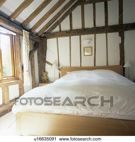 White duvet on simple wooden bed in beamed country bedroom with apex ceiling View Large Photo Image Stock Image - White duvet on simple wooden bed in beamed country bedroom with apex ceiling. Fotosearch