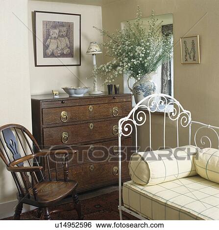 White iron bed in cottage bedroom with antique chest-of-drawers and chair View Large Photo Image Stock Photograph - White iron bed in cottage bedroom with antique chest-of-drawers and chair. Fotosearch