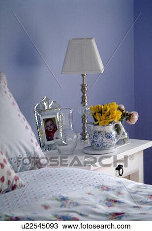 White lamp on bedside table in blue country bedroom View Large Photo Image Stock Image - White lamp on bedside table in blue country bedroom. Fotosearch