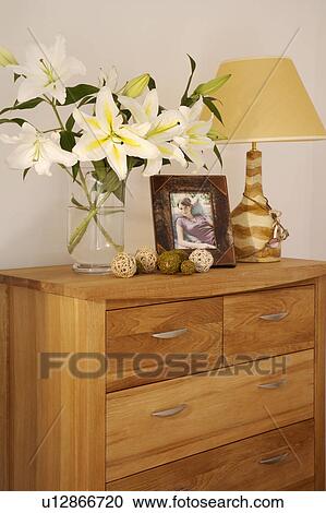 White lilies and cream ceramic lamp on modern wooden chest of drawers View Large Photo Image Stock Image - White lilies and cream ceramic lamp on modern wooden chest of drawers. Fotosearch