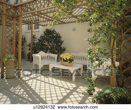 White painted wooden table and chairs below trellis pergola on patio in townhouse courtyard View Large Photo Image Stock Image - White painted wooden table and chairs below trellis pergola on patio in townhouse courtyard. Fotosearch