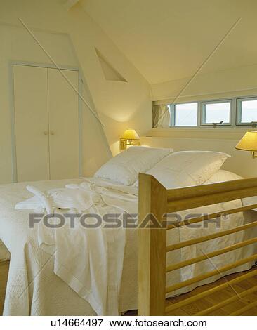 White pillows and linen on bed with white quilt in small white country attic bedroom with lighted lamps View Large Photo Image Stock Photo - White pillows and linen on bed with white quilt in small white country attic bedroom with lighted lamps. Fotosearch
