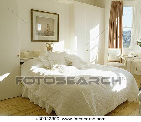 Stock Image - White quilt on bed in white country bedroom. Fotosearch