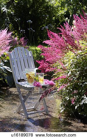 Stock Photo - White table and chairs in grassy corner of rough mown lawn.. Fotosearch