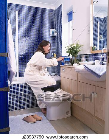Woman sitting on side of the bath in blue mosaic tiled bathroom View Large Photo Image Stock Image - Woman sitting on side of the bath in blue mosaic tiled bathroom. Fotosearch