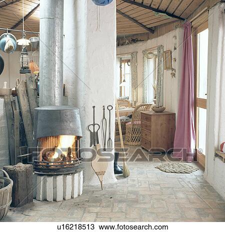 Stock Image - Wood-burning stove in sixties country hall with brick flooring. Fotosearch