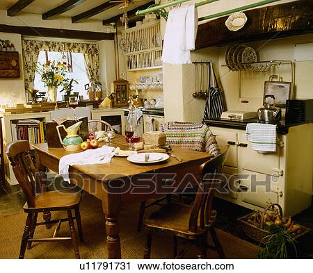 Wooden chairs and table in white cottage kitchen with cream Aga View Large Photo Image Stock Image - Wooden chairs and table in white cottage kitchen with cream Aga. Fotosearch